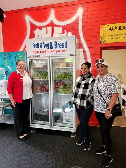 Three women standing with a refrigerator