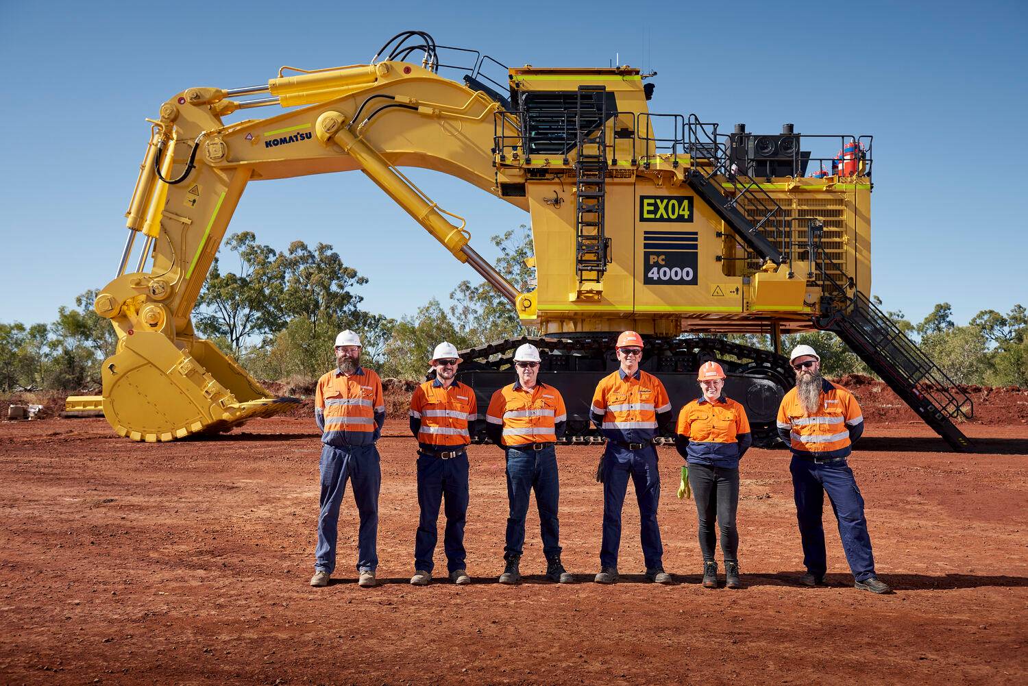 Group of workers standing in front of Komatsu mining machine