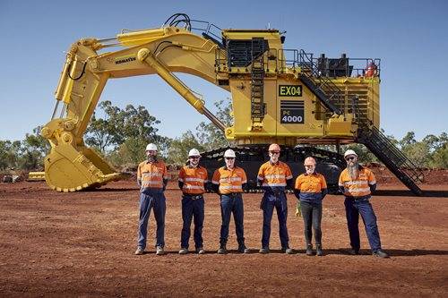 Group of workers standing in front of Komatsu mining machine