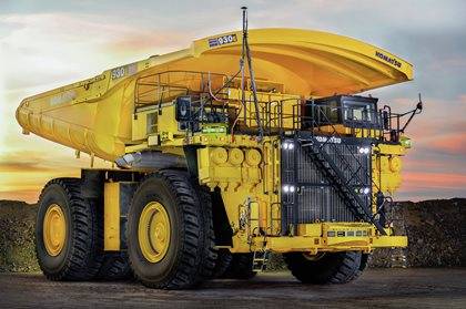 Komatsu 930E haul truck parked on a mining site at dusk.