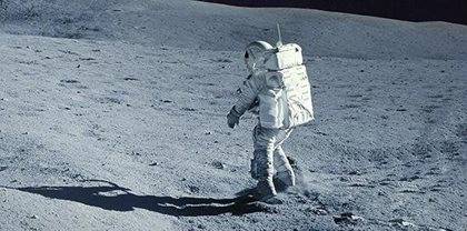 An astronaut in a spacesuit explores the lunar surface, characterised by a dusty, rocky terrain under a bright light.