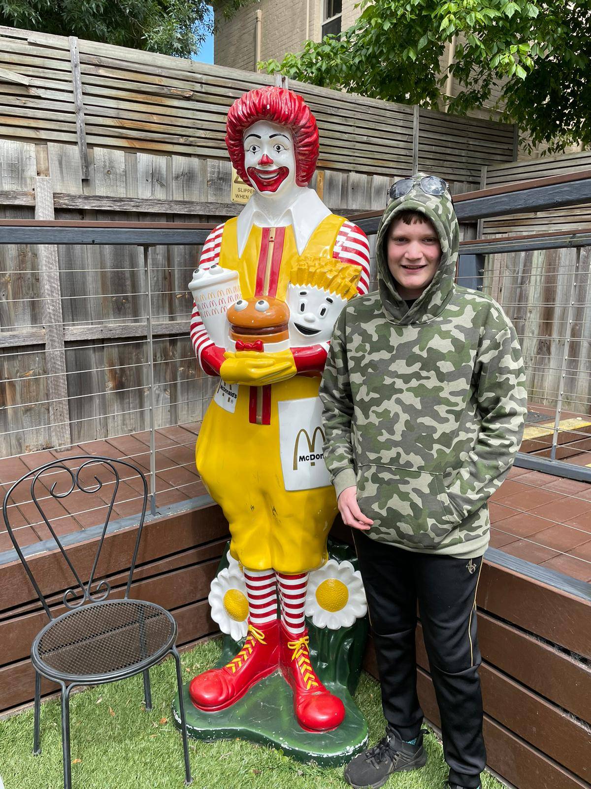 Person standing next to a Ronald McDonald statue in a courtyard.