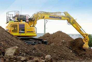 A yellow construction excavator digging on a pile of dirt.
