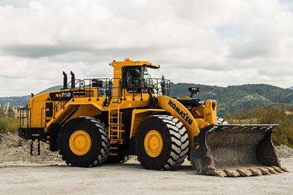 A Komatsu WA700-8 wheel loader parked on a gravel surface with a cloudy sky in the background.